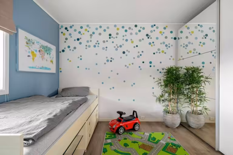 This child's bedroom features a white wall adorned with colorful blue and green polka dot decals.
