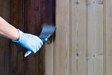 applying dark stain to unfinished wooden planks