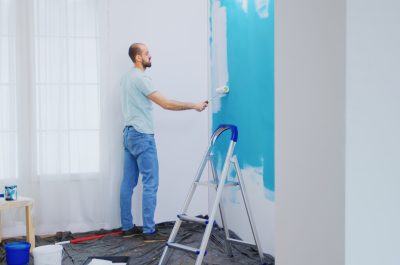 Painting apartment wall Painting apartment wall with white paint using roller brush. Handyman renovating. Apartment redecoration and home construction while renovating and improving. Repair and decorating.