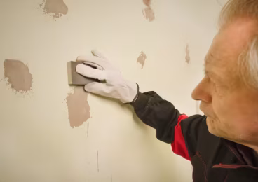 person sanding patched areas